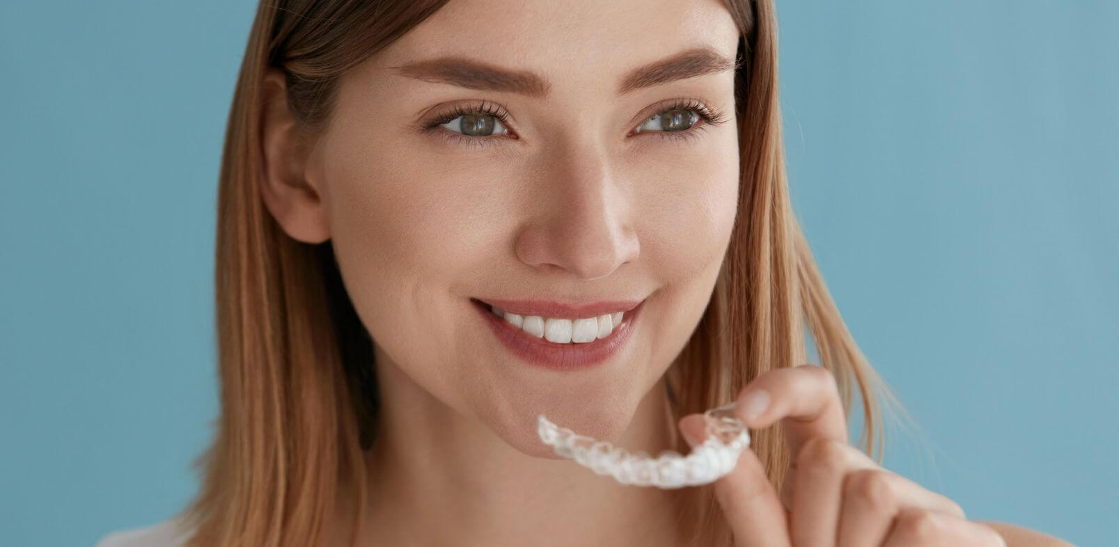 Woman putting in Invisalign braces at Ripon dental practice